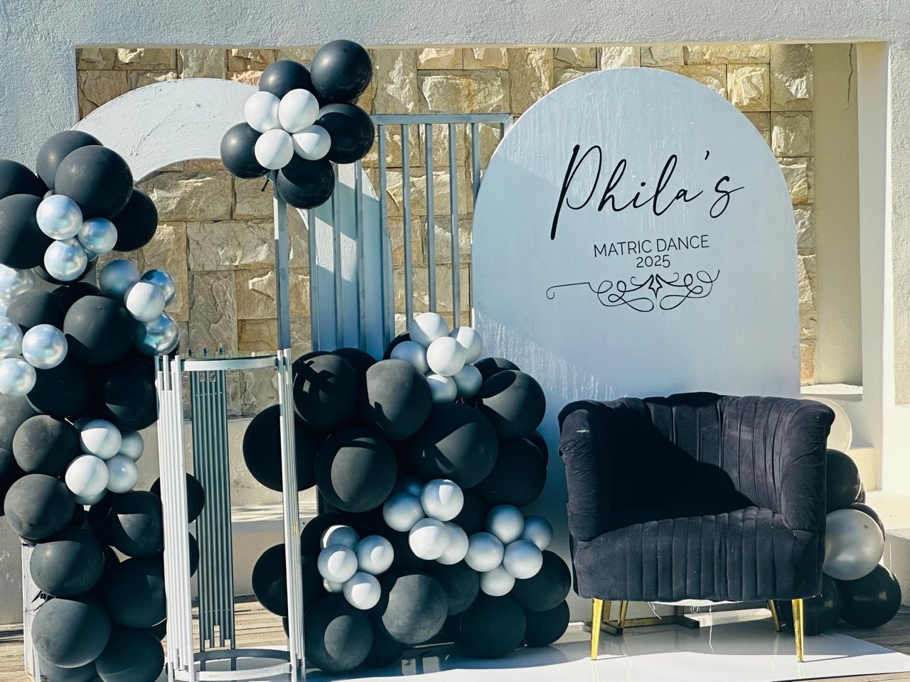 Matric dance backdrop with black and silver balloon garland and arch signage