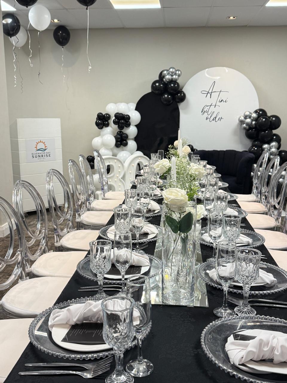 Long banquet table with ghost chairs and mirrored centrepieces
