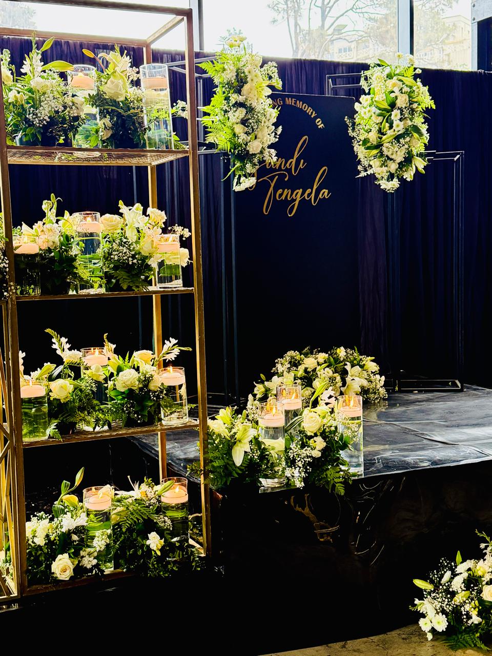 In loving memory backdrop with gold lettering, lilies and floating candles