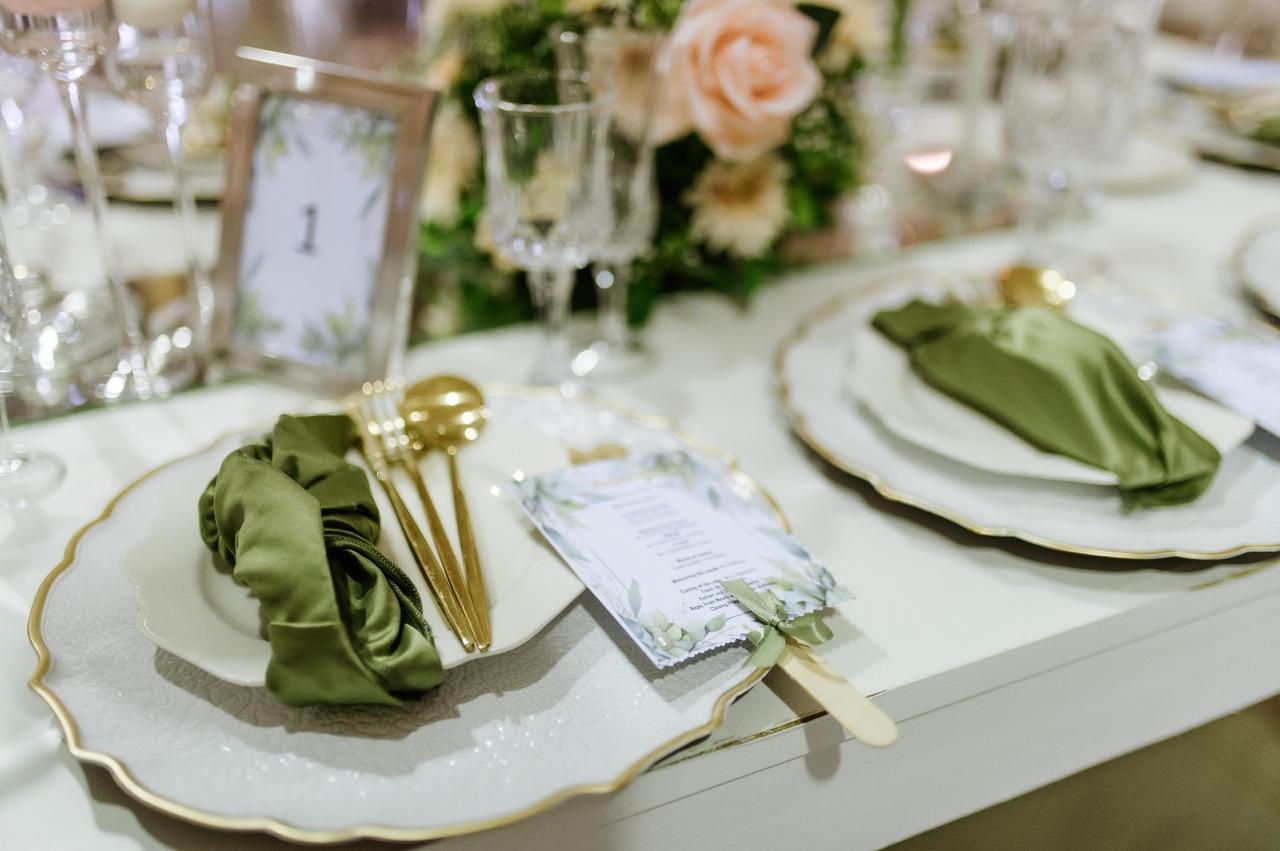 White and gold place setting with olive green napkins and menu fans