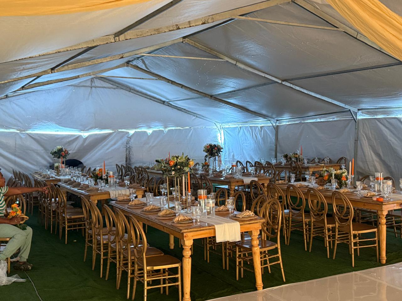 Marquee with wooden tables and gold chairs set for Ulwamkelo Lwabayeni