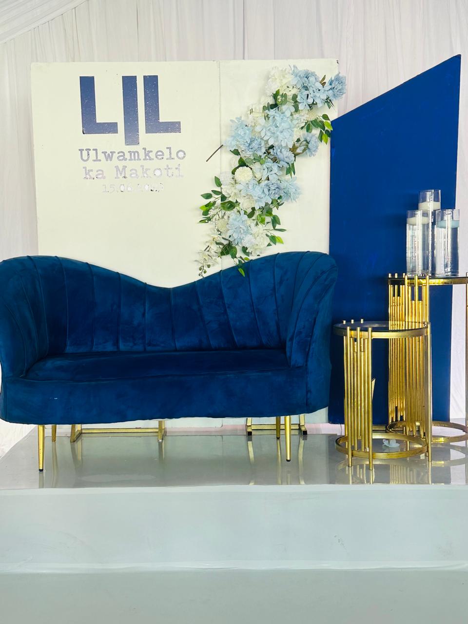 Ulwamkelo ka Makoti backdrop with navy velvet couch, blue florals and gold plinths
